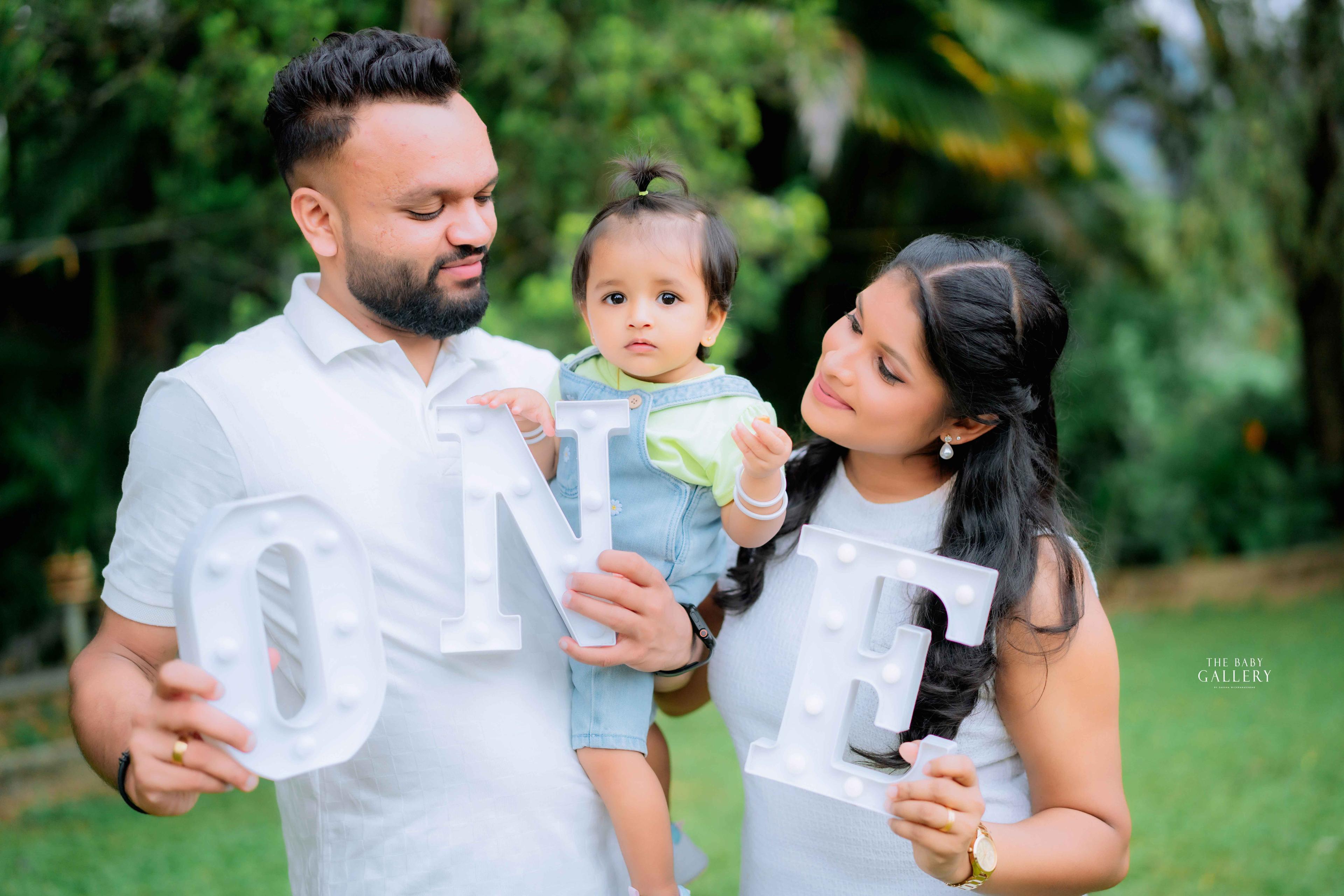 Parents holding their baby with letters spelling ONE for a first birthday shoot