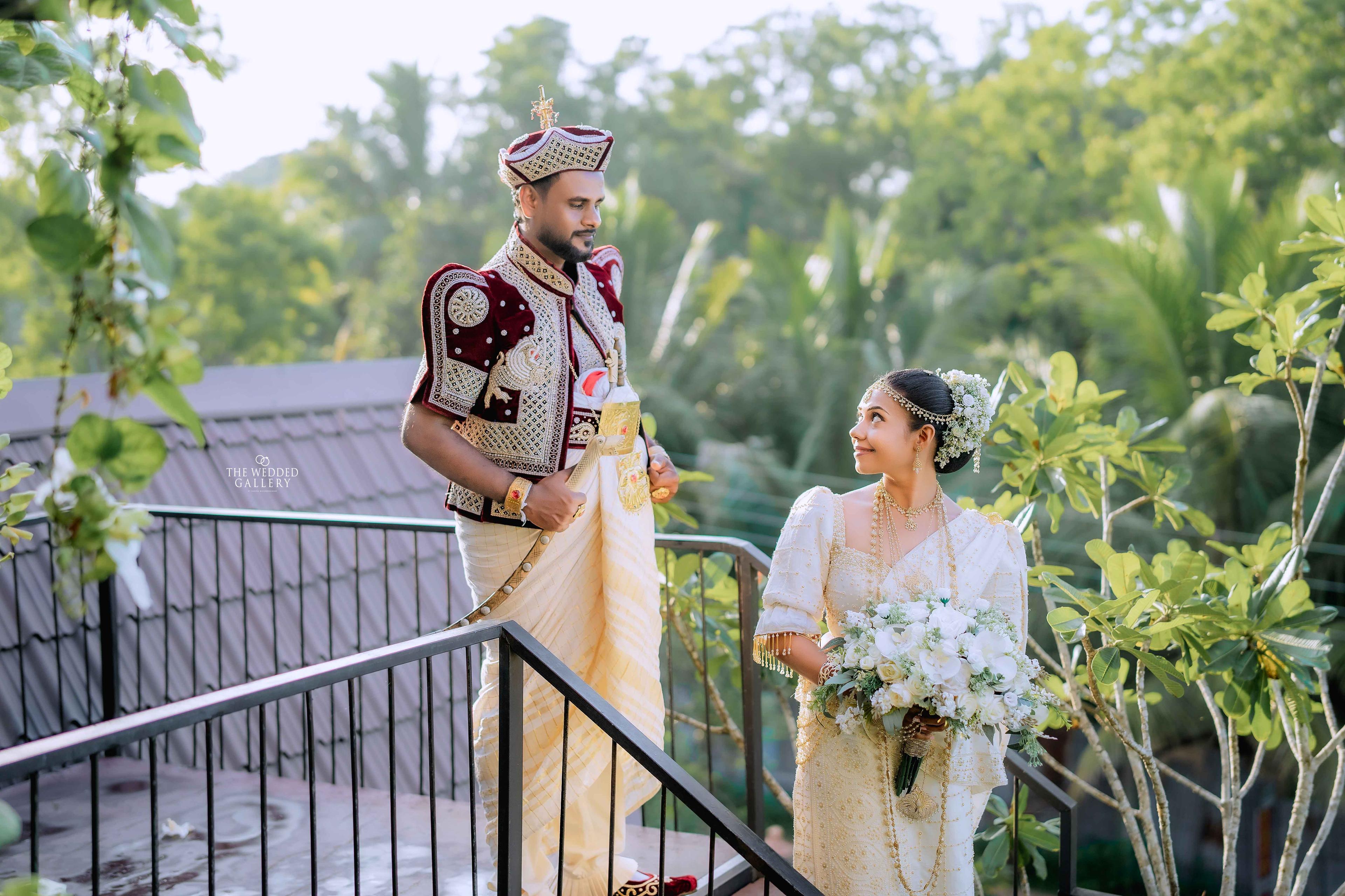 Kandyan groom and bride with a white bouquet on a leafy hotel balcony